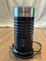 Front view of Keurig milk frother showing body, logo and power cord