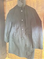 Full view of black overcoat hung on hanger