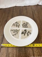 Front view of plate with tape measure showing approx. 14-inch diameter and botanical design