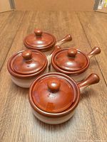 Four matching stoneware bowls with lids displayed at angle