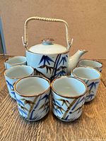 front view of teapot surrounded by six cups showing bamboo motif
