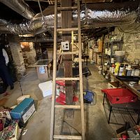 Full view of wooden straight ladder leaning against post in basement