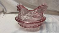 Full view of pink glass hen on nest covered dish showing lid and base