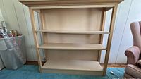 Front view of light wood 3-shelf bookcase showing full structure and shelves