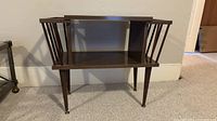 Front view of end table showing spindle magazine racks, open shelf and tapered legs