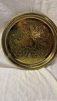 Full view of round gold-plated brass tray showing pierced rim and etched design