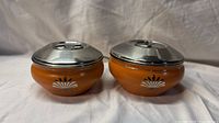 Pair of orange enamel condiment bowls with stainless lids