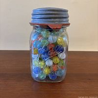 Front view of Ball Perfect Mason jar filled with marbles, lid and gasket visible