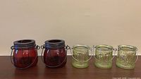 Group view of two red and three green glass candle holders
