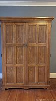 Closed oak armoire front view showing paneled doors and crown molding