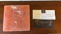 Front view of 8" square pink salt plate alongside instruction card