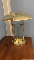 Front view of brass table lamp showing domed shade, glass panel, base