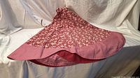 Full view of red floral tree skirt with gingham border displayed on white backdrop