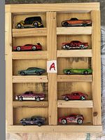 Full view of 11 Hot Wheels cars in wooden display