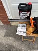 Wen chainsaw on small table with bar guard, Laser oil jug, manual visible