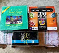 Three Trivial Pursuit boxed games on table