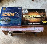 Front view of two boxed DVD games Scene It? Deluxe Edition and Deal or No Deal on small table