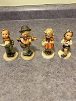Front view of all four Hummel figurines standing side by side