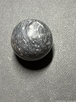 Black and gray polished marble sphere on textured surface