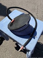 Top view of blue bellows foot pump showing black ribbed foot plate and hose attachment