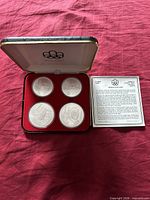 Open case displaying four coins and certificate
