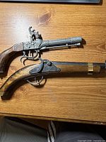 Two replica flintlock pistols on wooden surface