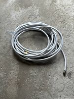 Coiled white reinforced water hose showing brass coupling