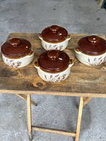 Four matching ceramic soup bowls with lids on wooden stand