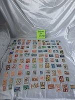 Full lot of 100 Greek stamps laid out on fabric background with note identifying lot