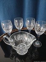Front view of four cut crystal wine glasses and one matching gravy boat