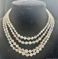 Necklace displayed on black bust showing four strands of iridescent crystal beads