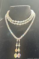 Two necklaces layered on display bust showing bead size, double and single strand construction, pendant drops, iridescent coating