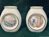 Front view of both porcelain bud vases showing Fragonard scenes and gold trim