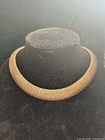 Front view of bronze-tone torque choker on display bust