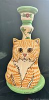 Front view showing orange tabby cat design and candle cup