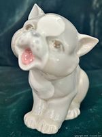 Front view of white porcelain cat figurine showing open mouth and facial detailing