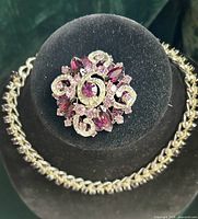 Necklace displayed on bust with brooch pinned above, showing overall design and colour coordination