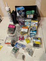Overview of all packaged screws, anchors, nails, caulk tube and storage bin