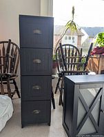 Full front view of tall black cabinet with four drawers