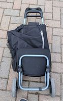 Cart folded flat showing wheels, frame and attached bag
