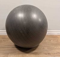 Full view of dark grey exercise ball on wood floor