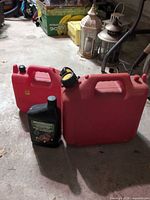 Front view of two red gasoline jerry cans and MotoMaster engine oil bottle