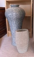 Large glazed vase and smaller stone-finish vase standing side by side