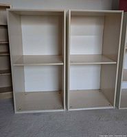 Front view of both shelving units showing adjustable middle shelves and drilled side holes