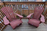 Two red-brown wooden Adirondack chairs on deck