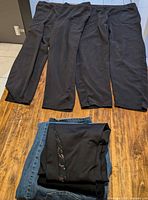 Three black knit pants laid flat on tabletop