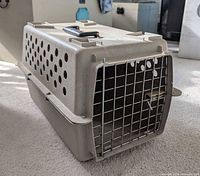 Three-quarter view showing crate body, ventilation holes, metal door, top handle