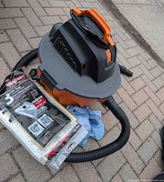Ridgid orange/black wet-dry vacuum with hose and filter bags package on pavement