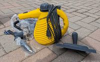 Steam cleaner with cord and attachments on pavement