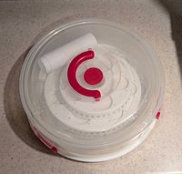 Top view of plastic cupcake carrier showing red handle and interior tiered tray